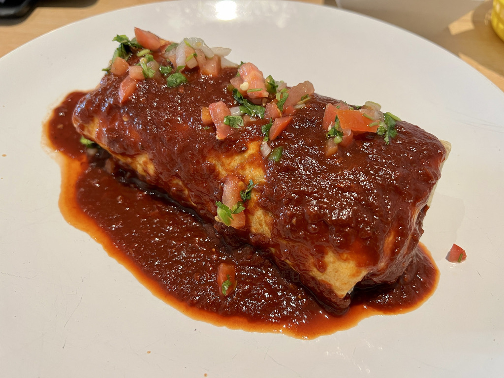 Tasty burrito covered in red sauce.